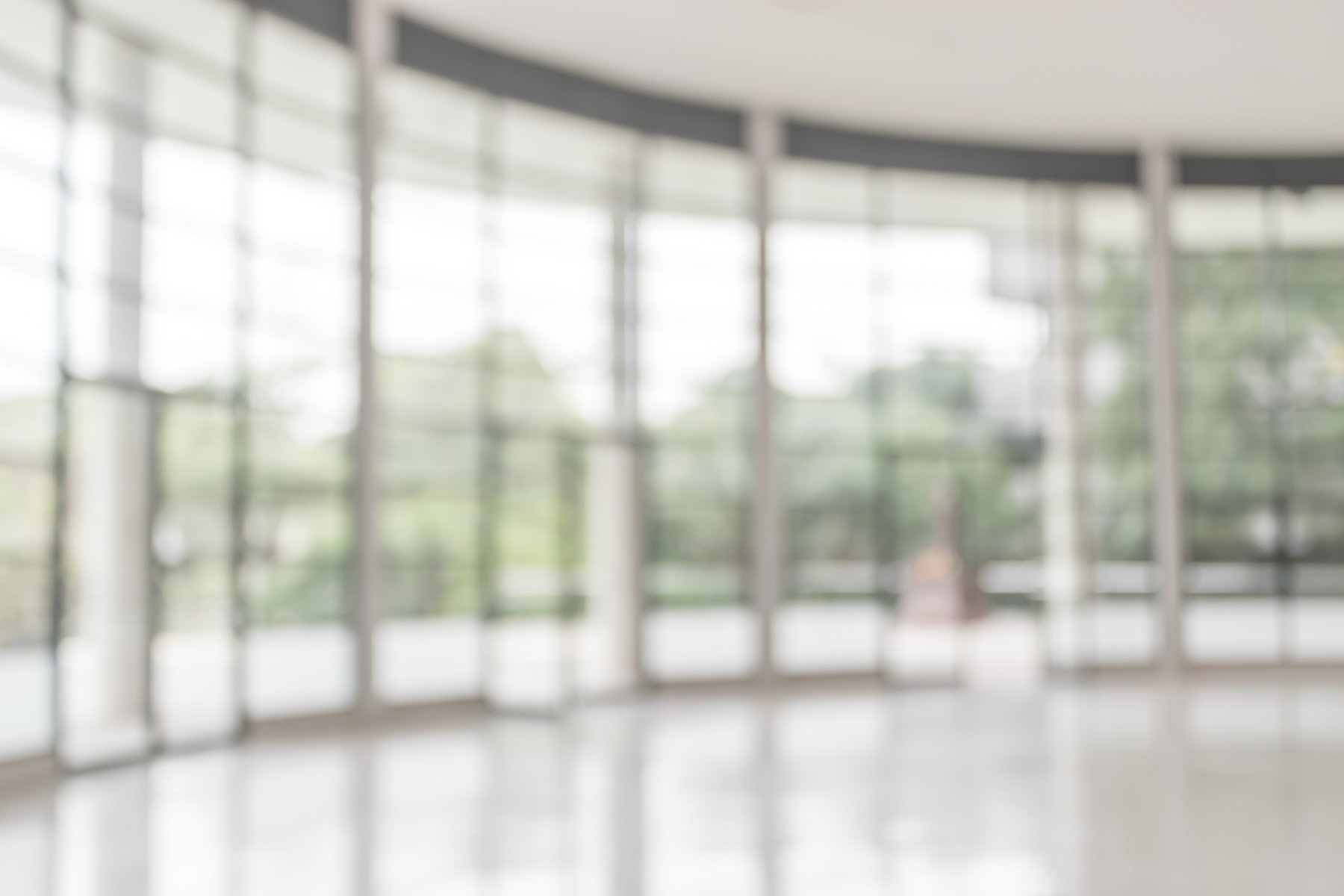 Blur background interior view looking out toward to empty office lobby and entrance doors and glass curtain wall